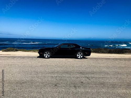 a black car in front of the blue ocean