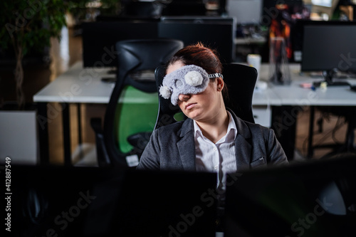 Business woman in a mask blindfolded asleep in the office. Exhausted employee in the workplace