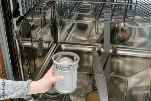 Woman hand put filter to the dishwasher machine.