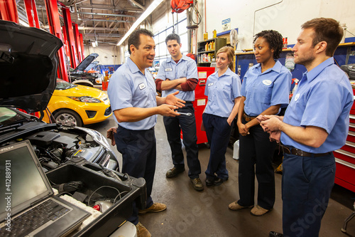 Men and women of diverse ethnic backgrounds, a team of mechanics in an auto repair shop photo