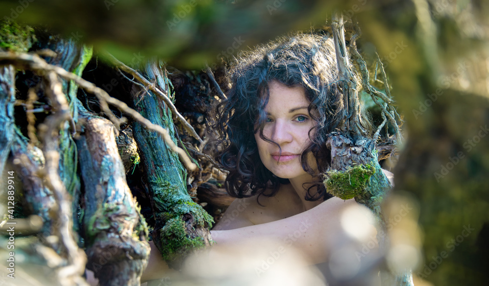 Portrait of a beautiful dark-haired young sexy thoughtful seductive woman in nature behind blue green vines Portrait of a beautiful dark-haired young sexy thoughtful seductive woman in nature behind blue green vines