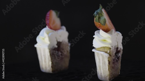 Delicious muffin cut into two halves with filling inside. Fresh strawberries. Spinning table. View from above. 4K.