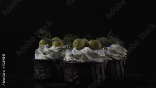 Three creamy ham and olives muffins. Delicious muffins. 4K. On a black background.