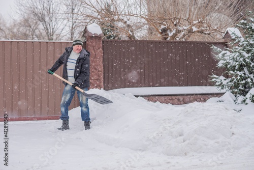 Snow collapse, man cleaning snow at winter weather with a shovel on a yard, winter trouble concept