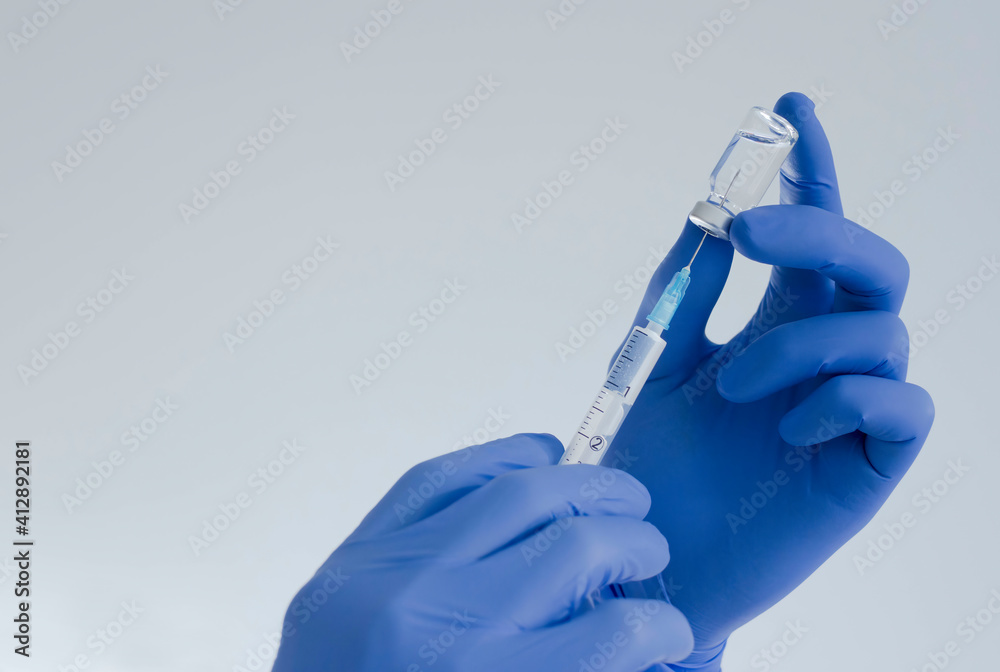 Doctor hands holding a vaccine bottle and syringe,beginning of worldwide mass vaccination for coronavirus COVID-19,influenza or flu,world immunization concept. Selective focus