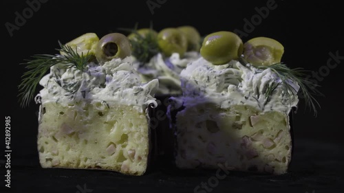 Creamy ham and olives muffins. Sectional view. Delicious dessert. 4K. On a black background.