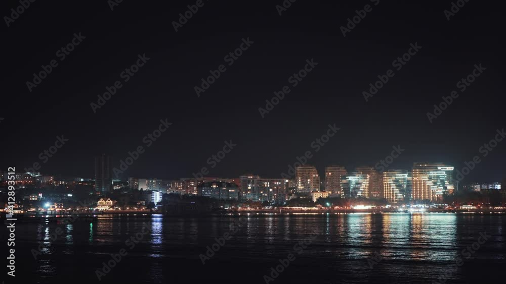 Panoramic view of Gelendzhik city resort seafront at night with illuminated modern buildings reflected in sea water. Panoramic view of Gelendzhik city resort seafront at night with illuminated modern buildings reflected in sea water.