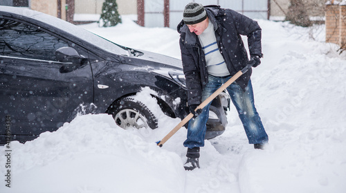 Winter, people and car problem concept. Man try on pushing the car, stuck in the snow. Mutual aid. Winter problem. transportation, winter and vehicle concept - closeup of man pushing car stuck in snow