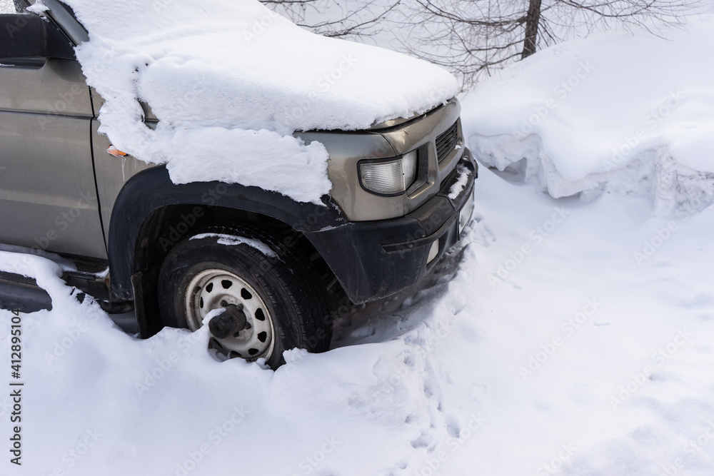 SUV car covered with snow among the trees. SUV car covered with snow among the trees.