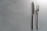 Fork and knife on white marble texture background. Concept for food and dining tableware