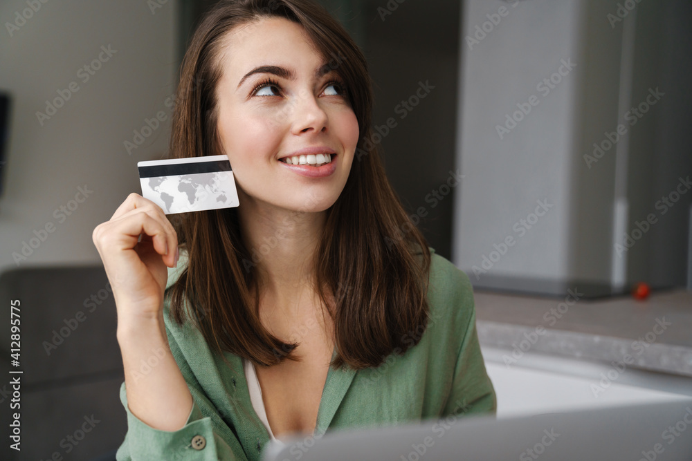 © Drobot Dean - Cheerful nice woman using credit card while working with laptop © Drobot Dean - Cheerful nice woman using credit card while working with laptop