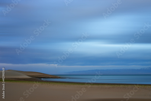 blurred view of plain at root of snow-covered mountains at sunset  © photollurg