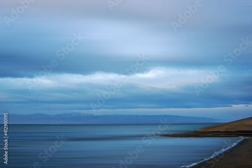blurred view of plain at root of snow-covered mountains at sunset  © photollurg