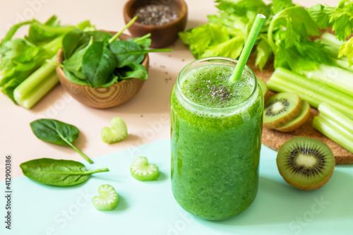 Healthy diet and nutrition, vegan, alkaline, vegetarian concepts. Green smoothie with celery, kiwi and spinach on a green pink background.