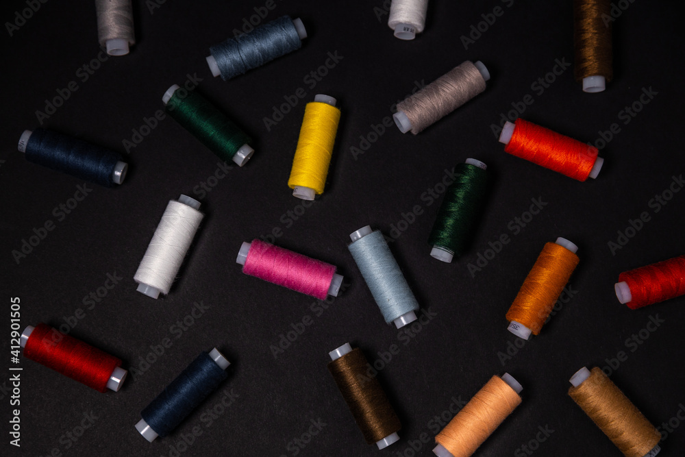 colored threads are scattered on a dark background. View from above.