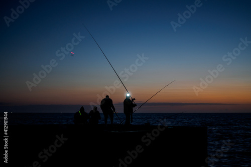 silhouette of man fishing in sunrise in front of sea