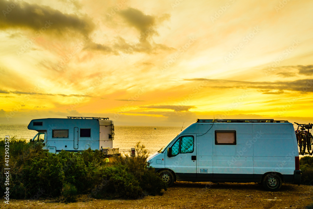 Camper vehicles on beach at sunrise