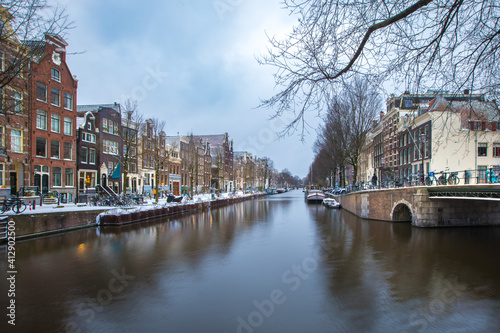 Winter snow view of Dutch canal and old houses in the historic city of Amsterdam, the Netherlands