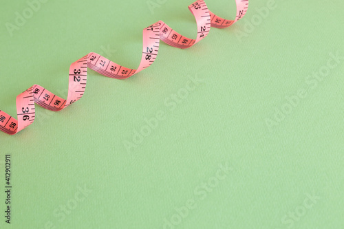 Pink tape measure on green background