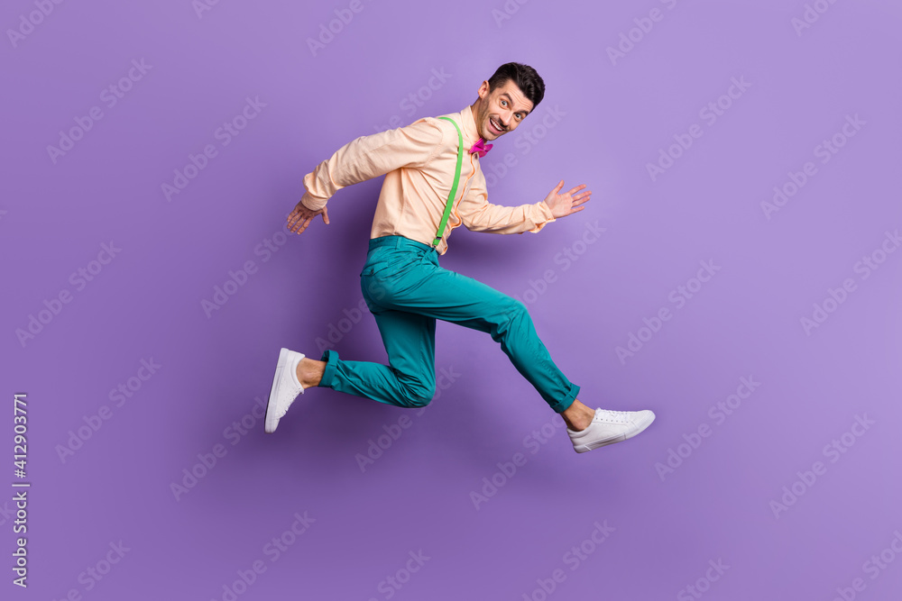 Full body profile side photo of young man run copyspace wear pink bow tie jump isolated on purple color background