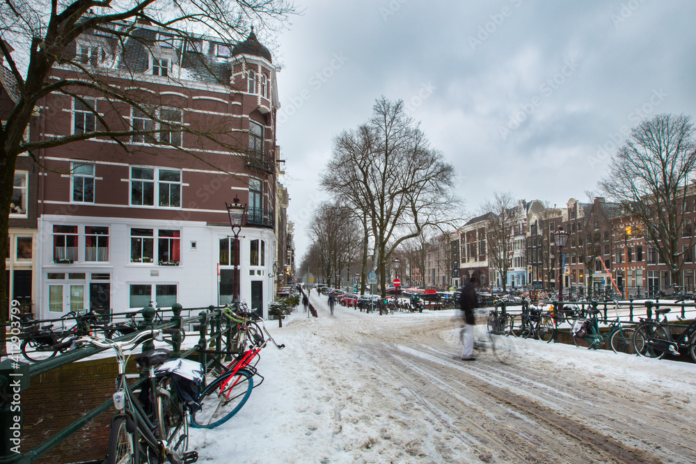 Winter snow view of Dutch canal and old houses in the historic city of Amsterdam, the Netherlands