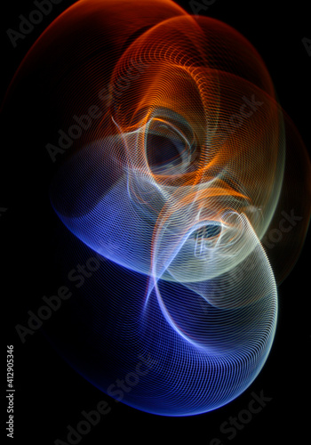 Long exposure photograph of multicolored light trails forming a complex twisted geometric pattern of parallel lines against a dark background.