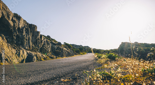 Empty long mountain road to the horizon on a sunny summer day at bright sunset