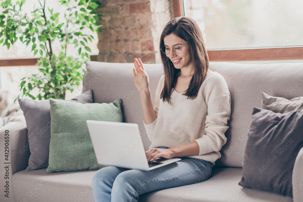 Photo of pretty young lady talk computer web camera laptop wave hello online meeting sit sofa inside home indoors Photo of pretty young lady talk computer web camera laptop wave hello online meeting sit sofa inside home indoors
