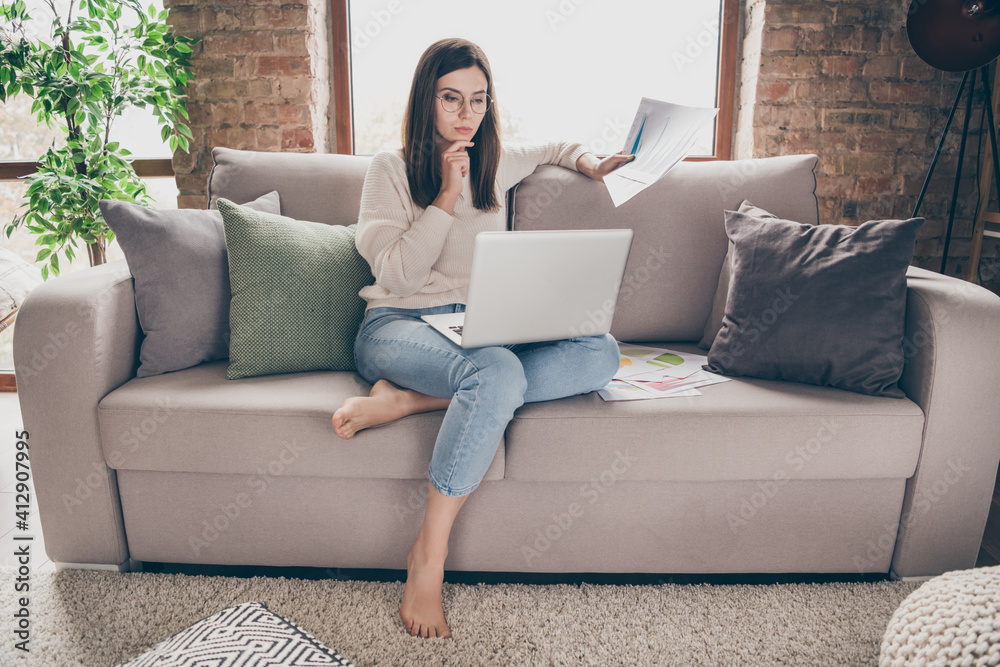 Photo of serious focused woman hold paperwork hand chin look laptop remote work inside home indoors house Photo of serious focused woman hold paperwork hand chin look laptop remote work inside home indoors house