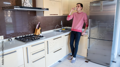 A man drinking a cup of water on the kitchen