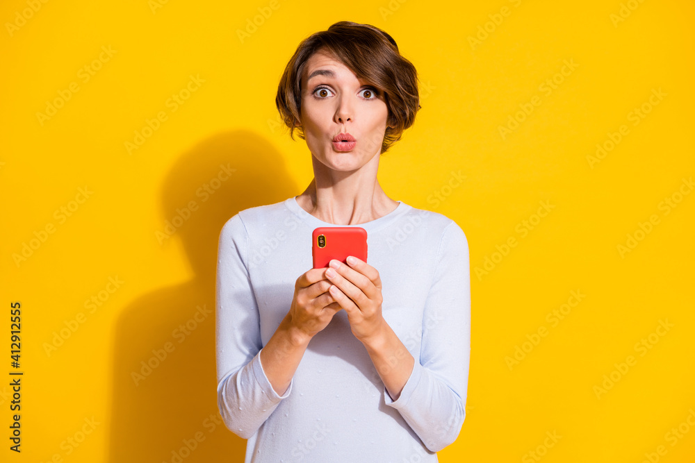 Photo of shocked lady hold phone look camera amazed face wear white shirt isolated yellow color background