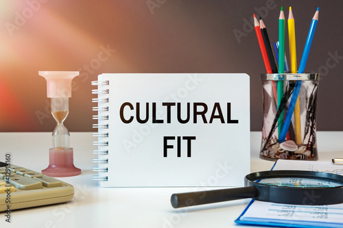 CULTURAL FIT is written on a notepad on an office desk