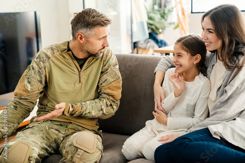 Masculine military man gesturing while talking his happy family