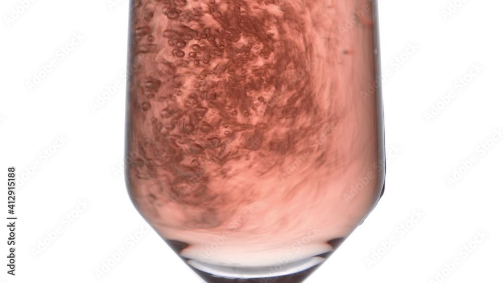 Closeup of glass with sparkling rose wine decorated gold star confetti, celebration party on white background
