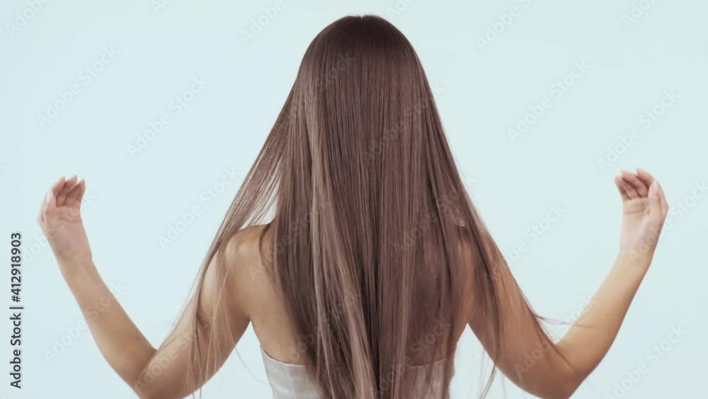Woman moves long hair. Rear view. Girl shakes long straight hair. Female model is fluttering hair.   Slow motion footage. Rear view. Ginger. Red haired.