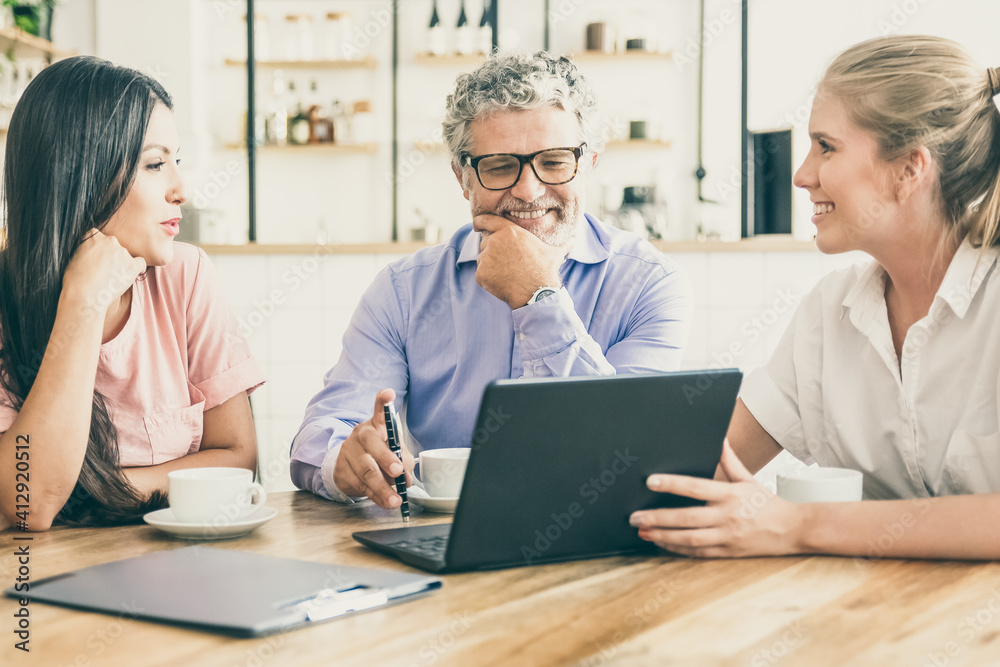 Happy female manager presenting project on laptop to young woman and mature man, discussing content with satisfied customers. Consulting or communication concept Happy female manager presenting project on laptop to young woman and mature man, discussing content with satisfied customers. Consulting or communication concept