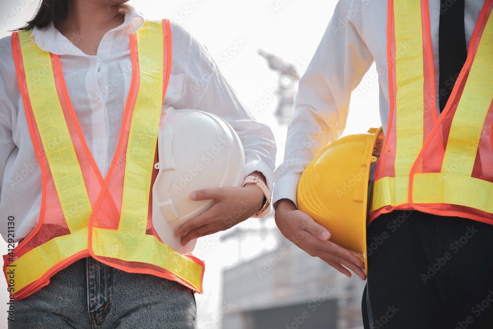 Male and female engineers holding helmets at workplaces Male and female engineers holding helmets at workplaces