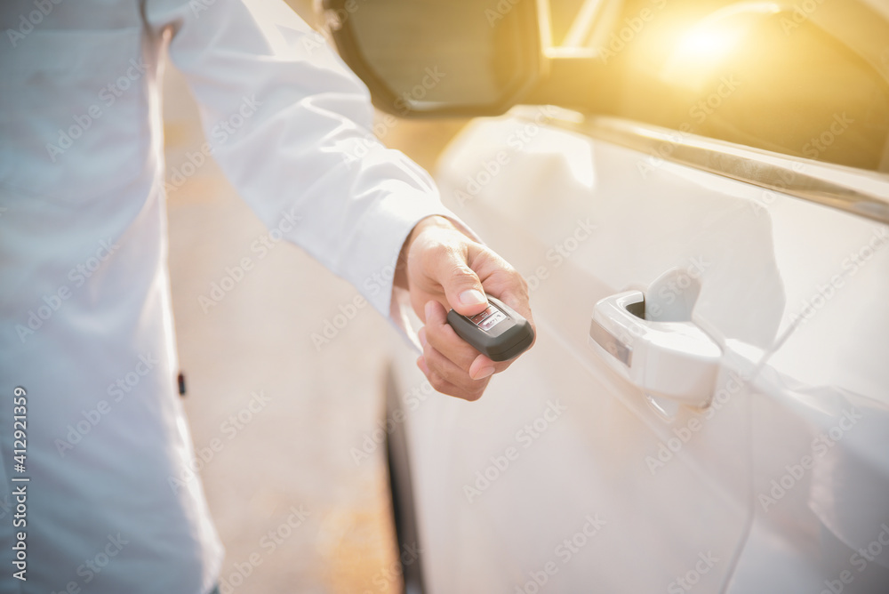 Car remote control by smart key, Hand holding smart key to lock doors of white car Car remote control by smart key, Hand holding smart key to lock doors of white car