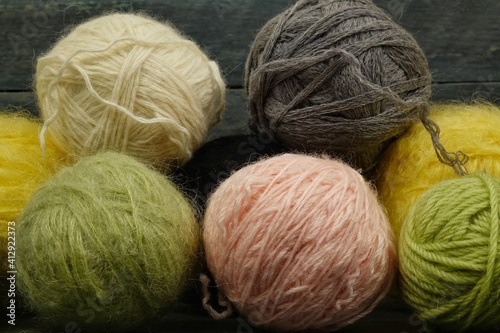 Balls of colored yarn for knitting on a dark wooden black background