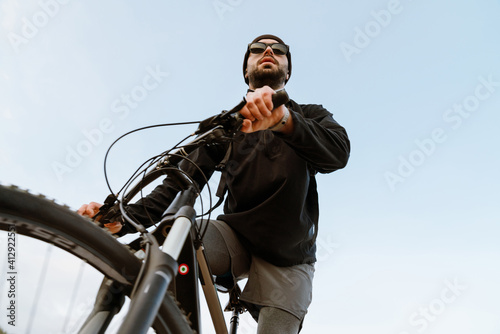Young focused sportsman riding his bicycle while working out