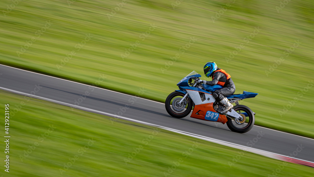 A panning shot of a racing motorbike as it circuits a track.