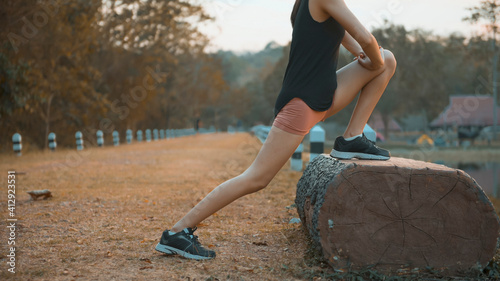 A young woman is warming up before running in nature outdoor at sunset .