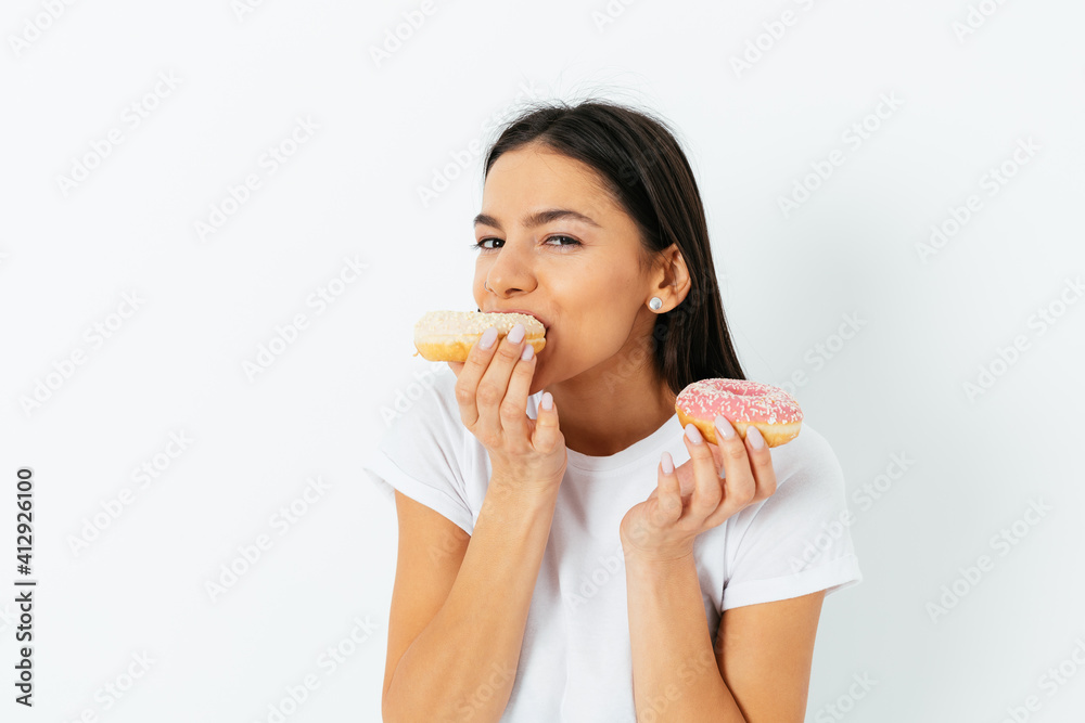 Portrait of joyful young woman eating donuts Portrait of joyful young woman eating donuts