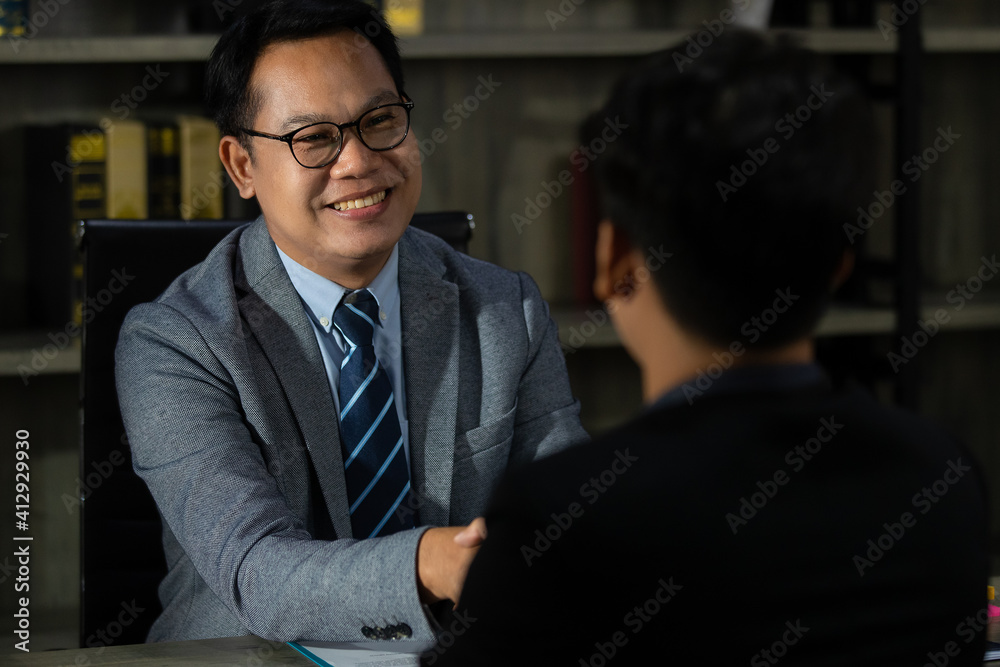 A senior businessman looks like CEO or executive or business owner in  luxury suite shaking hand with another one with a smiley and sincerely, successful manner. Idea for deal finishing in business