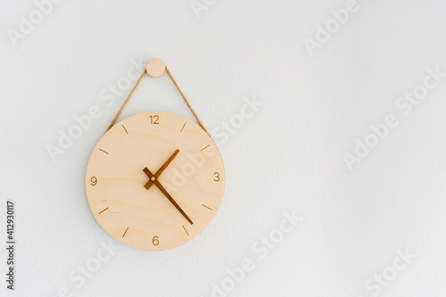 A wooden clock on a white cement wall