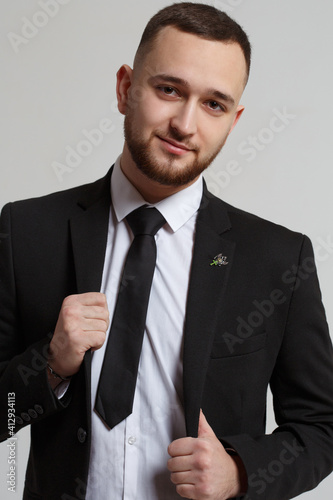 Young man with a beard in a business suit isolated on a gray background.