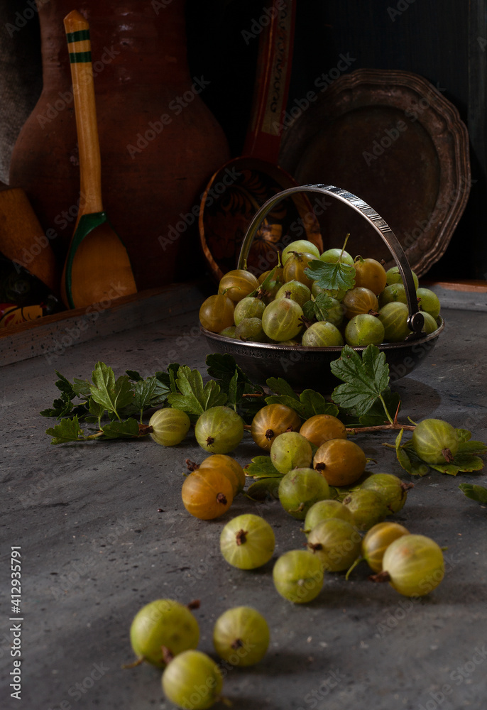 Gooseberries in metal bowl and scattered on the table in old vintage kitchen Gooseberries in metal bowl and scattered on the table in old vintage kitchen