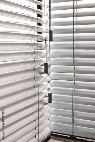 Aluminum blinds on the office windows. Made from metal. Venetian blinds closeup on the window. Silver color. Closed horizontal blinds in sunny day. Modern sun protection and window decoration.