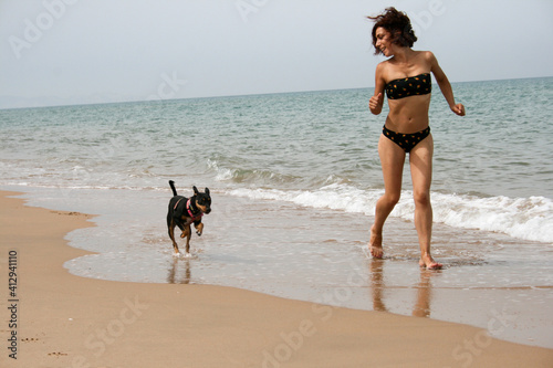Perro y chica en la orilla del mar