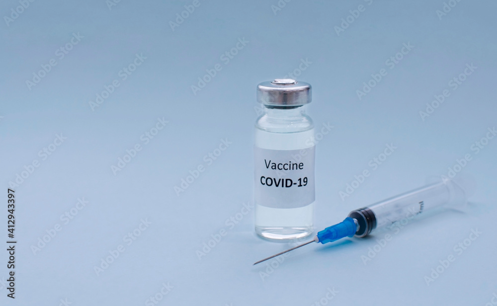 Syringe and COVID-19 vaccine on light blue background, copy space. Coronavirus vaccination and healthcare concept.